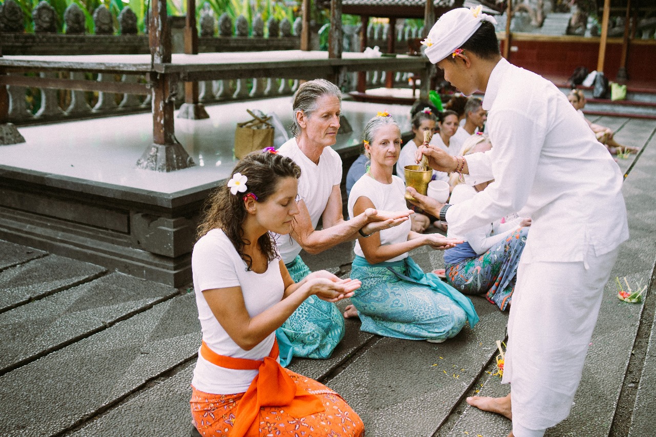 Yogis participate in a traditional Melukat ceremony at Tirta Gangga, a highlight of our Bali yoga teacher training and yoga holidays.