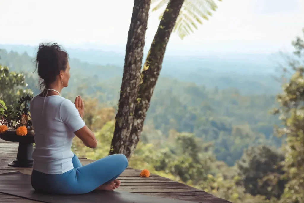 Tauchen Sie ein in die Gelassenheit: Ein Student findet Frieden in der Meditation inmitten der atemberaubenden Berglandschaft Balis, während er an unserem umfassenden 300-Stunden-Yogalehrer-Ausbildungsprogramm und Retreat teilnimmt.
