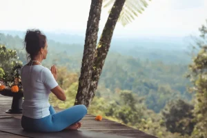 Tauchen Sie ein in die Gelassenheit: Ein Student findet Frieden in der Meditation inmitten der atemberaubenden Berglandschaft Balis, während er an unserem umfassenden 300-Stunden-Yogalehrer-Ausbildungsprogramm und Retreat teilnimmt.